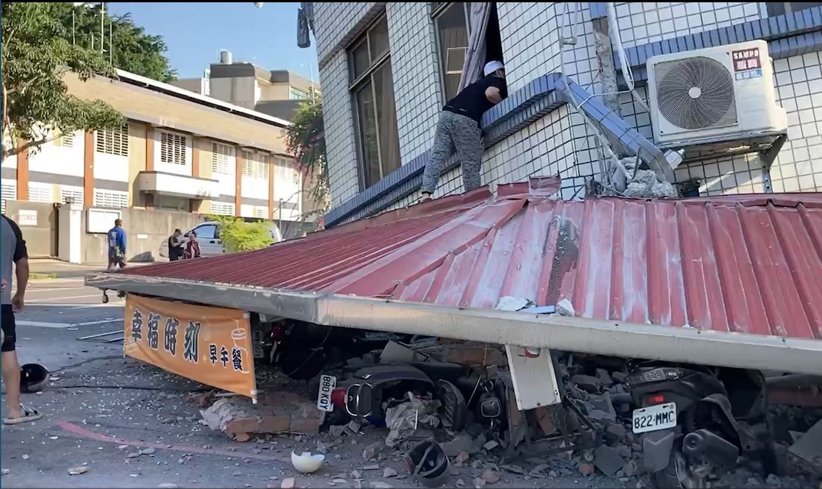民眾攀上鐵皮救援位於坍塌建物二樓的人。（讀者提供）